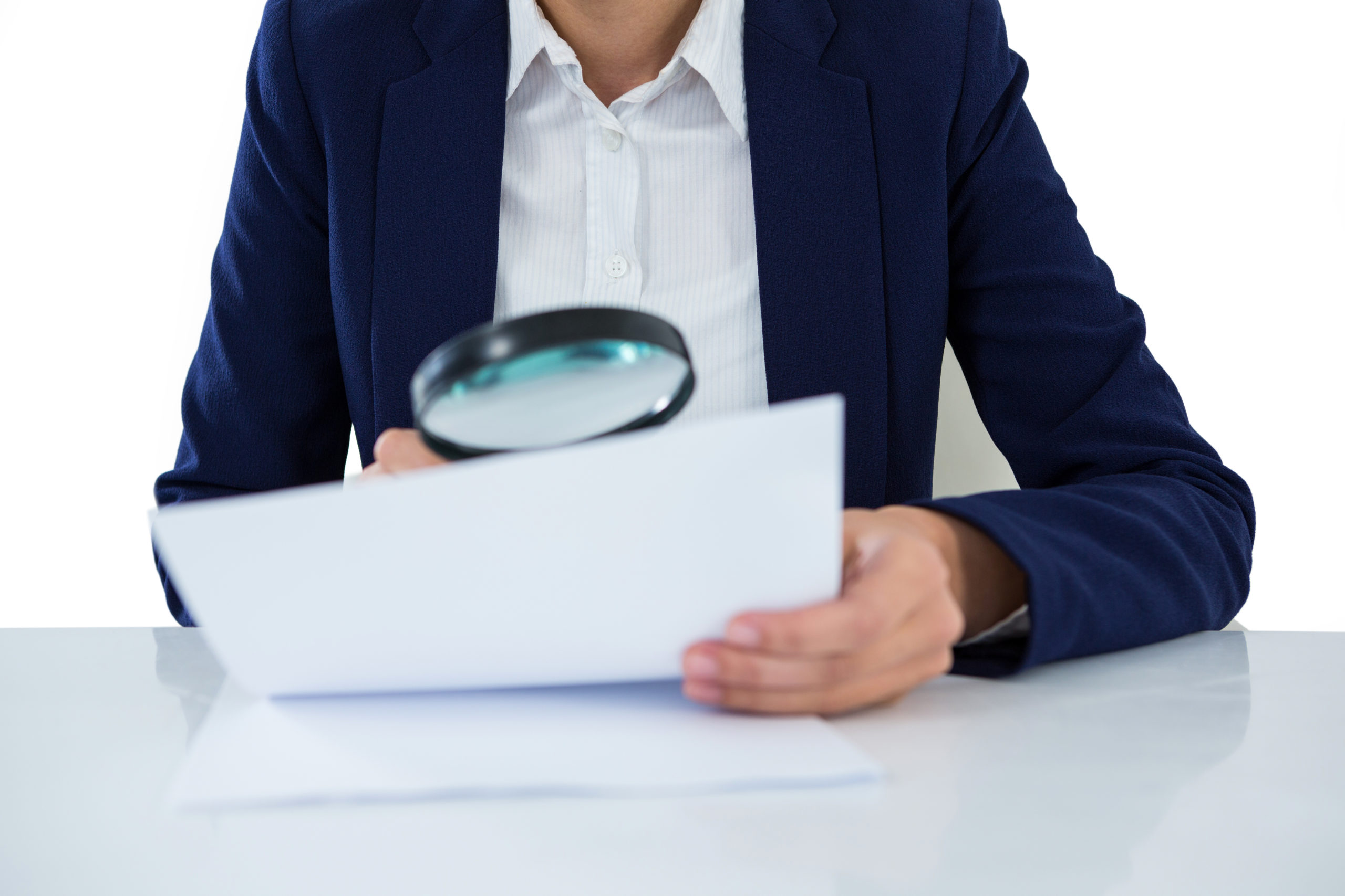Mid section of businesswoman looking at document through magnifying glass